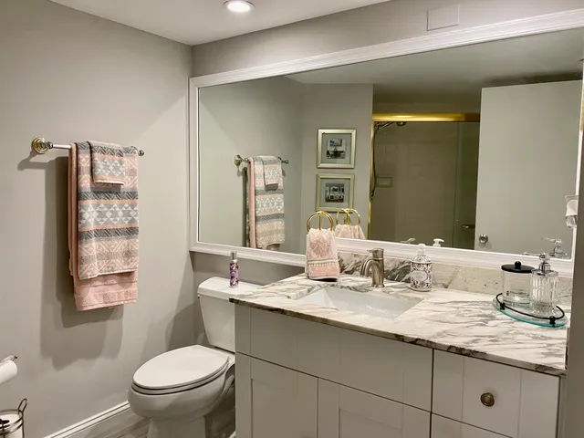 a bathroom with a granite countertop sink mirror vanity and toilet