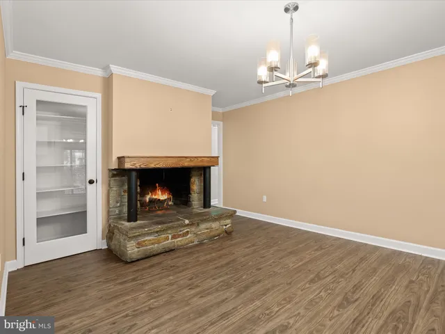 a view of kitchen and empty room with wooden floor fireplace
