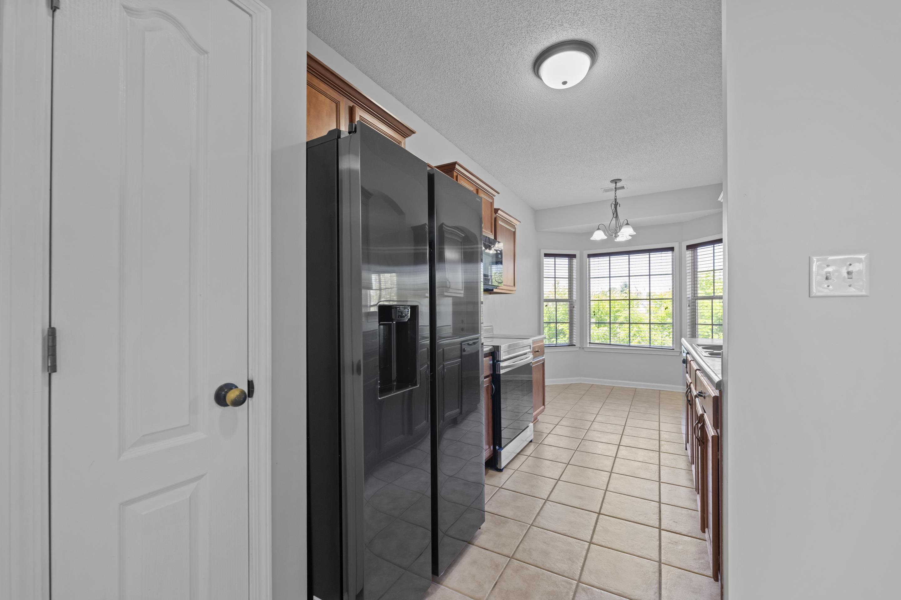 50 Abbey Road Oakland, TN 38060 - Photo 9 of 26 Kitchen featuring a black side-by-side refrigerator, wood cabinetry, tile flooring, and a bay window with a multi-pane design