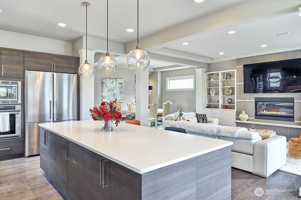3319 Burnett Avenue North Renton, WA 98056 - Photo 22 of 40 a large living room with stainless steel appliances granite countertop couches a fireplace kitchen island with wooden cabinets and chandelier