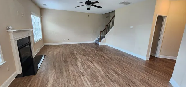 an empty room with wooden floor and a ceiling fan
