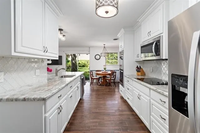 a kitchen with granite countertop a sink stove top oven and cabinets