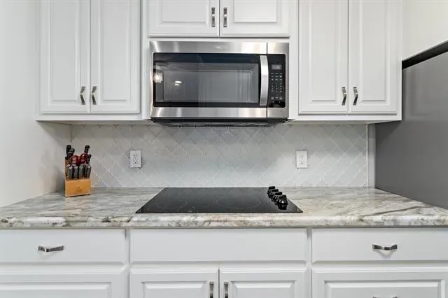 a kitchen with granite countertop white cabinets and a stove