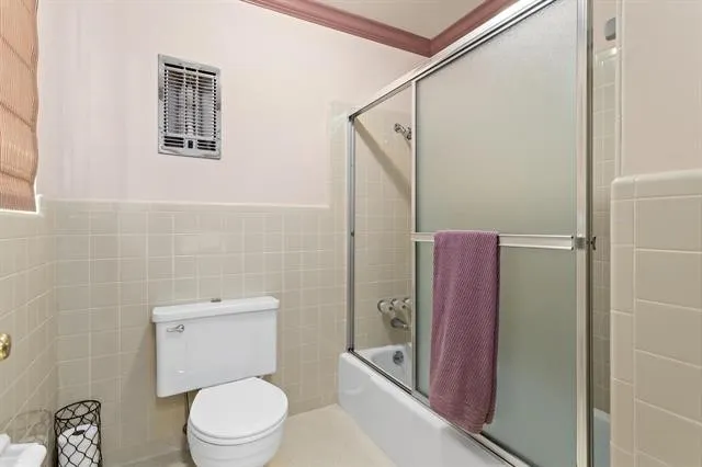 a white toilet sitting next to a bathroom sink and a shower