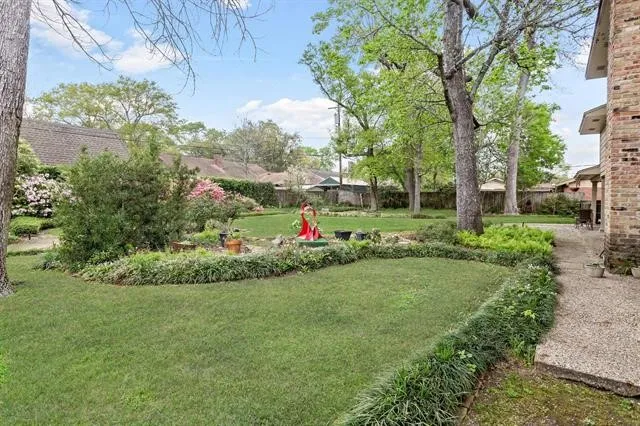 a view of a garden with a fountain and large trees