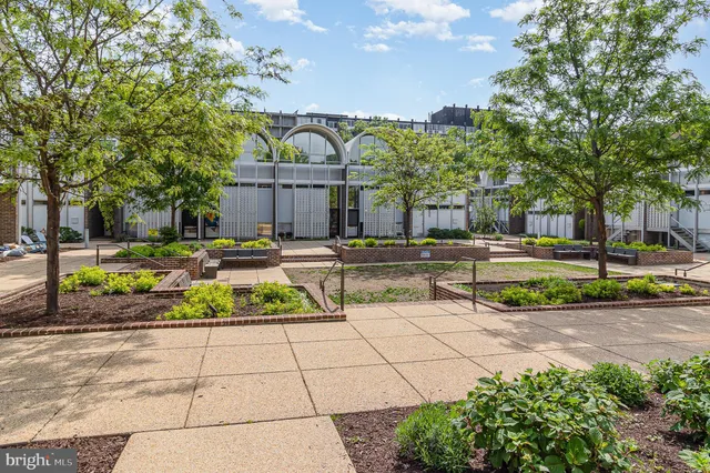 a view of a fountain with a bench in front of house