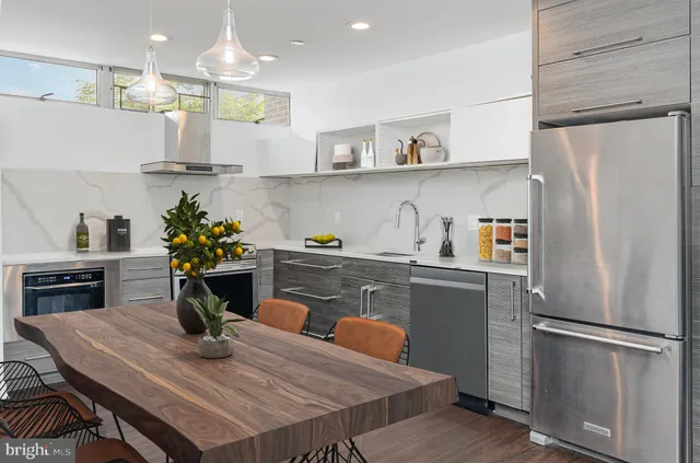 a kitchen with stainless steel appliances granite countertop a refrigerator a sink dishwasher a dining table and chairs with wooden floor