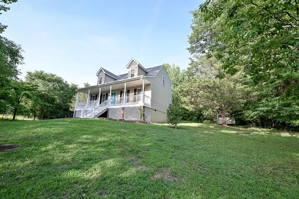 a view of a house with a big yard and large trees