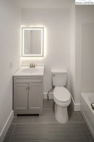 a bathroom with a toilet a sink a vanity and mirror