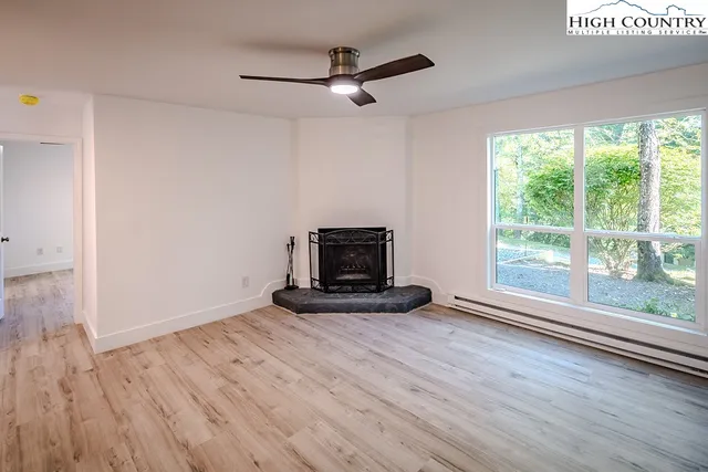 a view of a livingroom with wooden floor a fireplace and a window