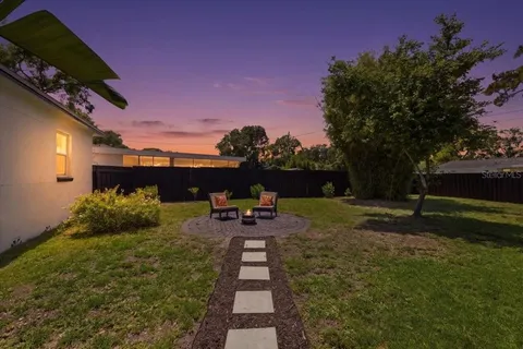a view of a backyard with couches plants and large trees