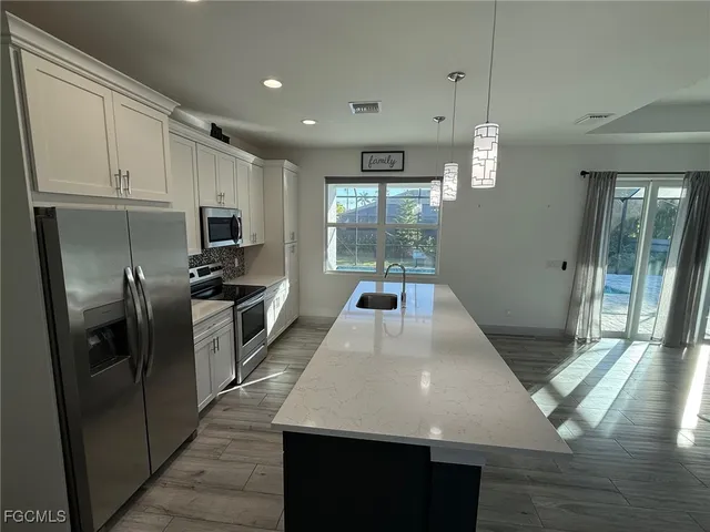 a large kitchen with kitchen island a counter space a sink appliances and cabinets