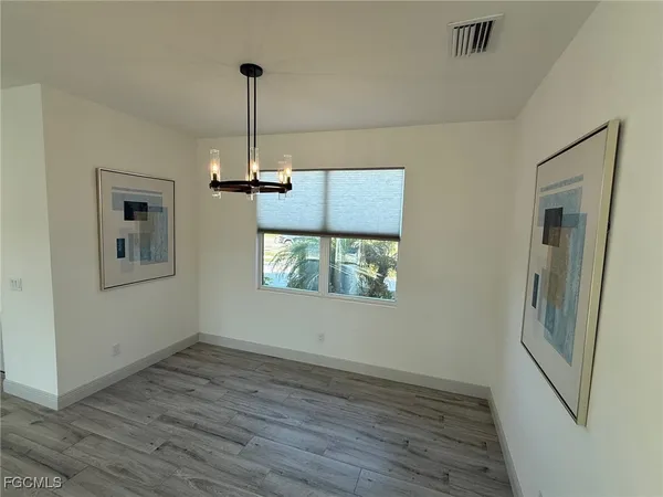 an empty room with wooden floor cabinet and windows