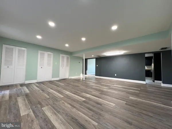 a view of an empty room with wooden floor and closet