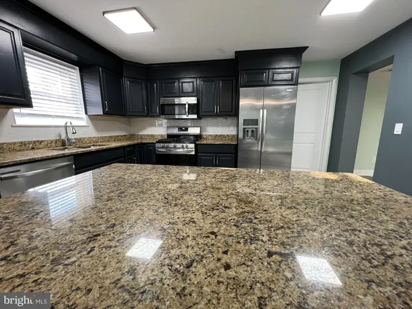 a kitchen with kitchen island a counter top space a sink stainless steel appliances and cabinets