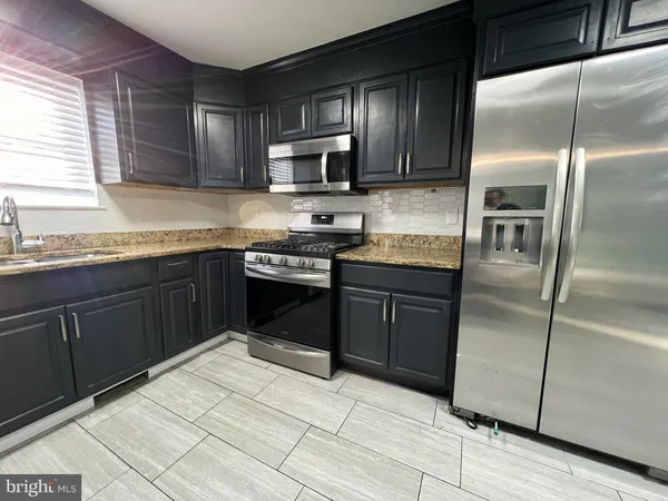 a kitchen with stainless steel appliances granite countertop a stove a sink dishwasher a refrigerator and a microwave oven with wooden cabinets