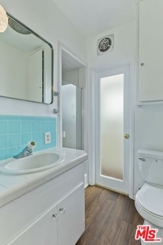 a spacious bedroom with a bed a mirror and a table with wooden floor