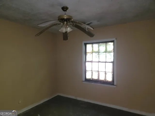 an empty room with a window and a fan