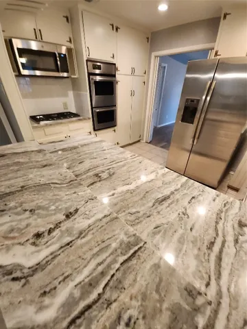 a kitchen with stainless steel appliances kitchen island granite countertop a stove a refrigerator and a sink