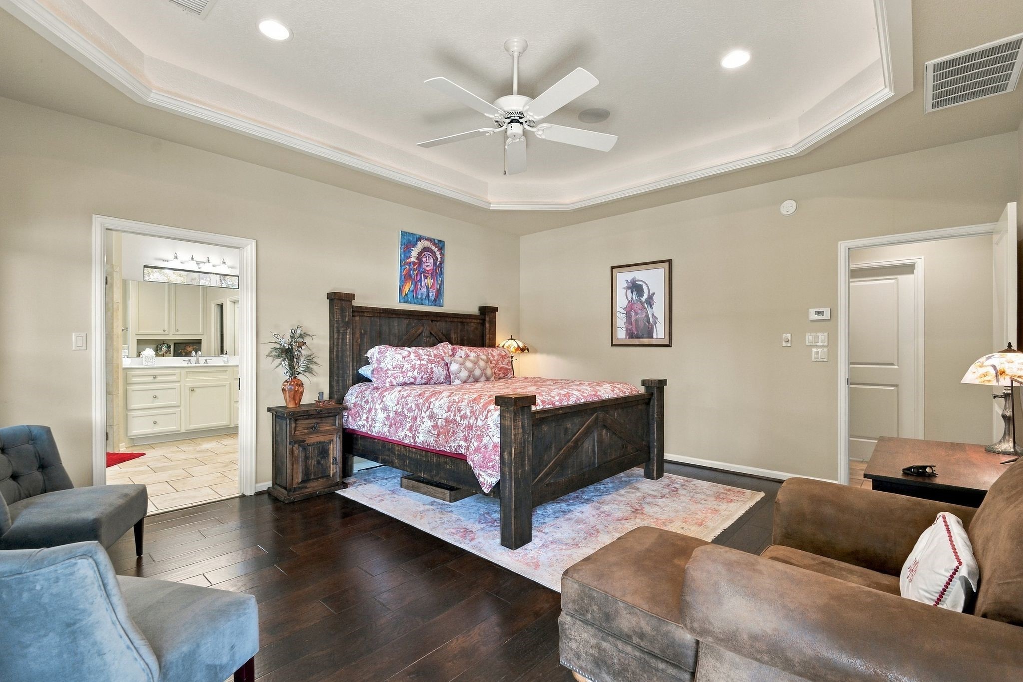 20341 Bay Hill Road Point Blank, TX 77364 - Photo 21 of 50 Expansive bedroom featuring elegant tray ceiling with recessed lighting, and rich hardwood floors. Cozy seating and direct access to a well-appointed en-suite bathroom enhance comfort and convenience.
