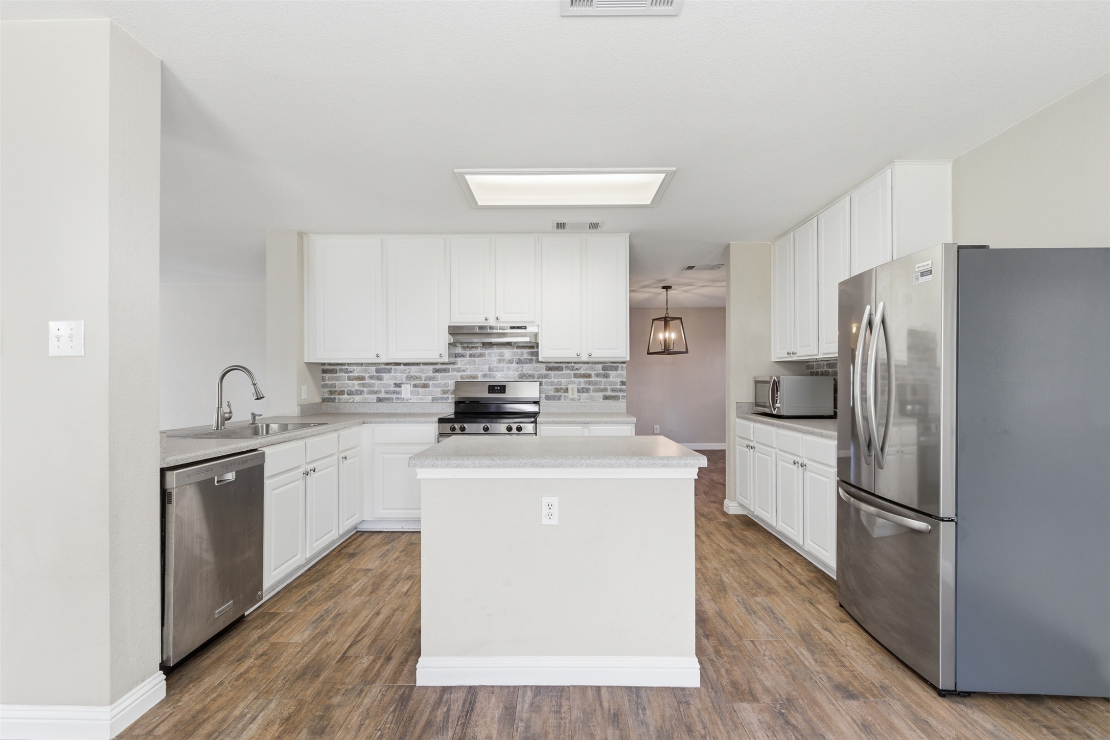 1715 Ruthie Run Cedar Park, TX 78613 - Photo 9 of 25 Kitchen featuring stainless steel appliances, light countertops, white cabinetry, a center island, and wood tile floors
