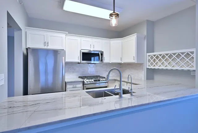 a kitchen with stainless steel appliances a sink a microwave a refrigerator and cabinets