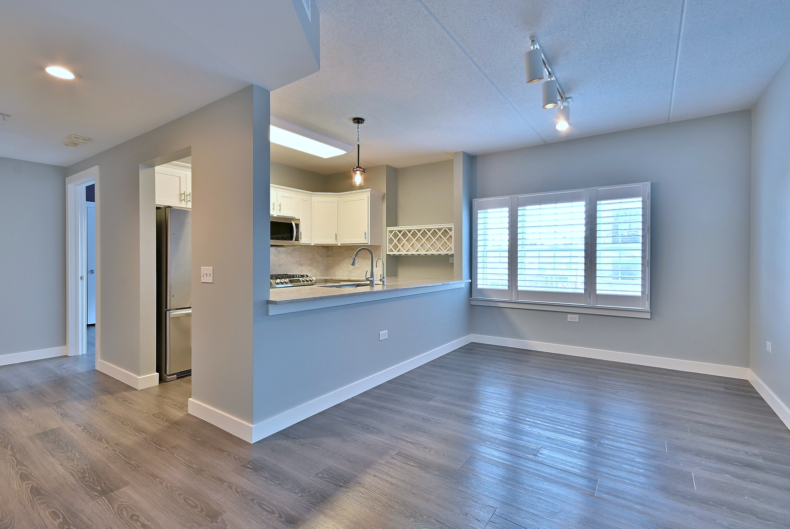 210 North Addison Avenue, Unit 303 Elmhurst, IL 60126 - Photo 7 of 20 an empty room with wooden floor and a kitchen