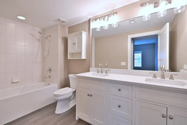 a bathroom with a double vanity sink toilet mirror and bathtub