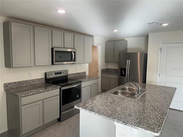 a kitchen with stainless steel appliances granite countertop a sink stove microwave and refrigerator