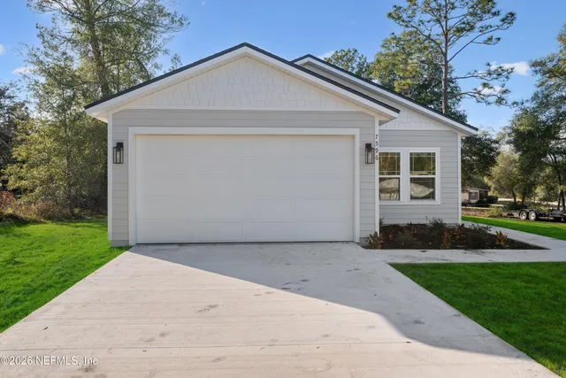 a view of a white house next to a yard and large trees
