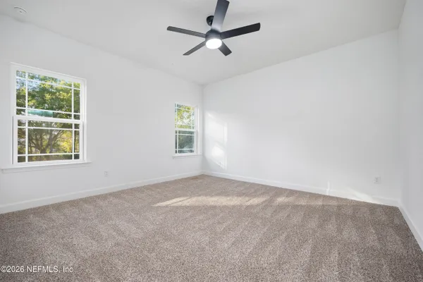 an empty room with windows and fan