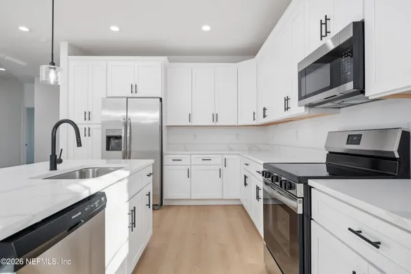 a kitchen with stainless steel appliances a stove microwave and sink