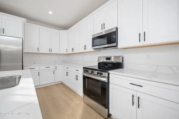 a kitchen with white cabinets and stainless steel appliances