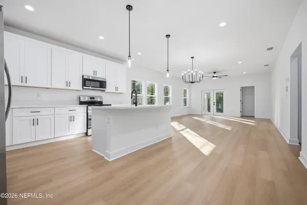 a large kitchen with kitchen island a stove a sink a center island and a wooden floor