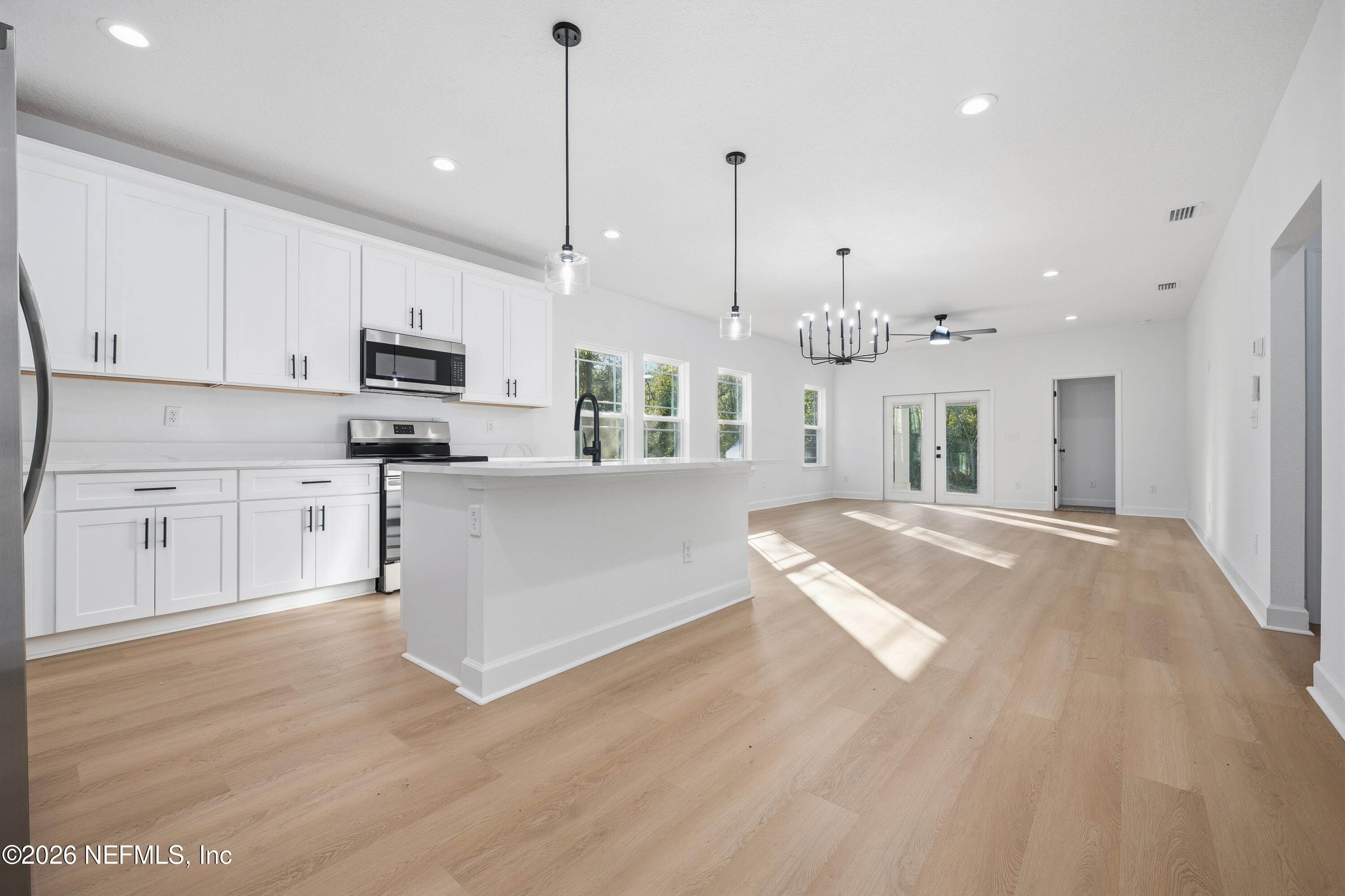 7596 Silver Sands Road Keystone Heights, FL 32656 - Photo 8 of 26 a large kitchen with kitchen island a stove a sink a center island and a wooden floor