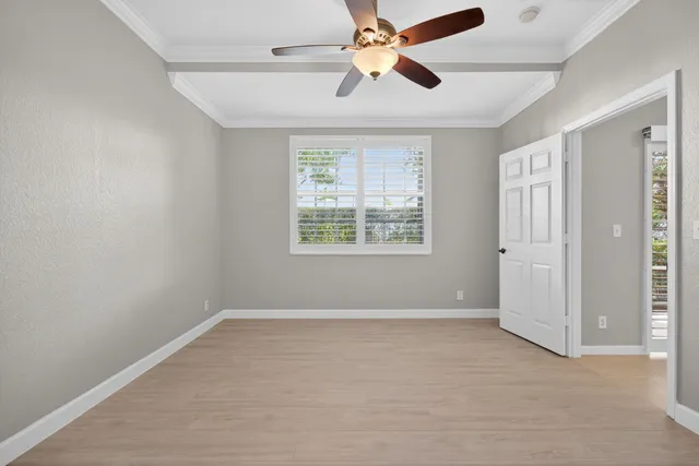 an empty room with wooden floor fan and windows