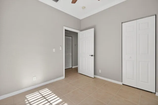 an empty room with a chandelier fan and windows