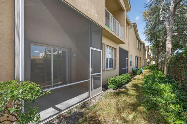 a view of a patio with a table and chairs under an umbrella with palm trees
