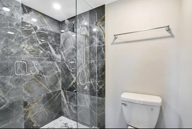a bathroom with a granite countertop sink toilet and mirror