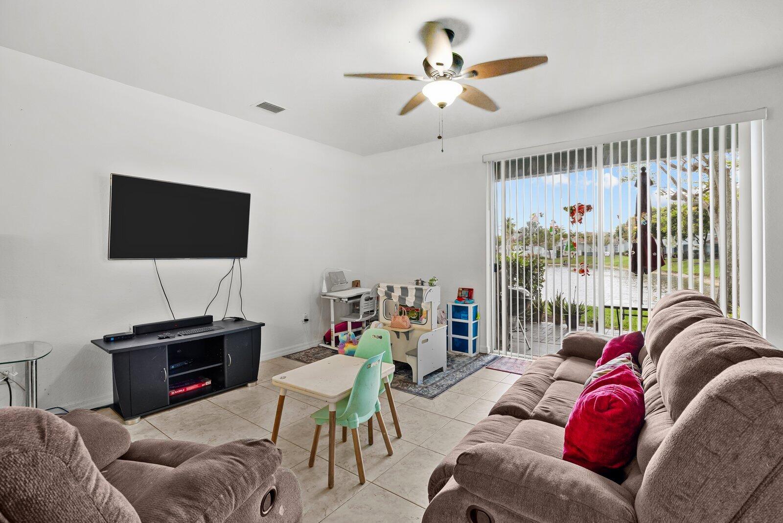 1955 Alamanda Way Riviera Beach, FL 33404 - Photo 3 of 25 a living room with furniture a ceiling fan and a flat screen tv