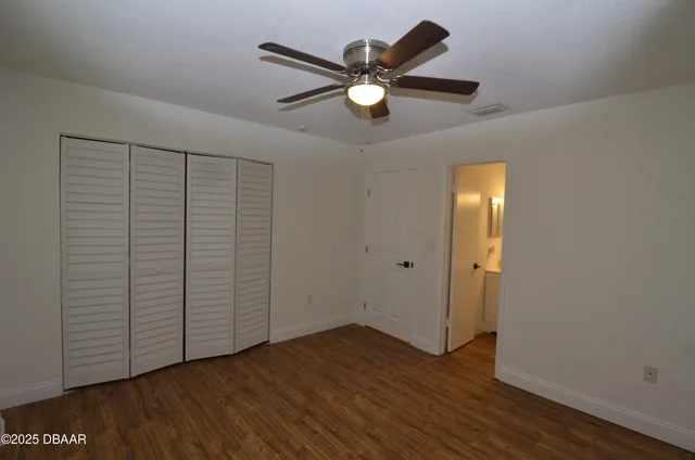 an empty room with wooden floor and ceiling fan