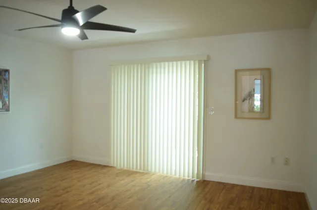 an empty room with ceiling fan and windows