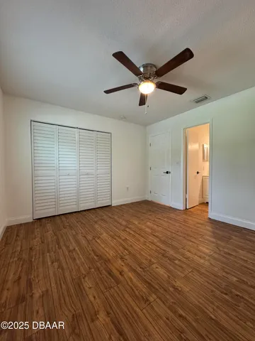 a view of empty room with wooden floor and ceiling fan