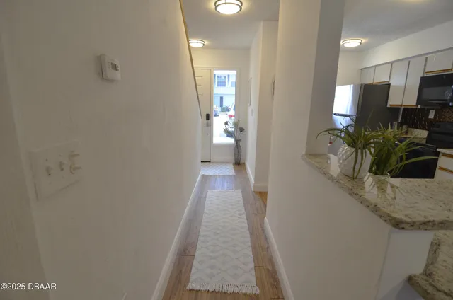 a view of a hallway with wooden floor and a bathroom