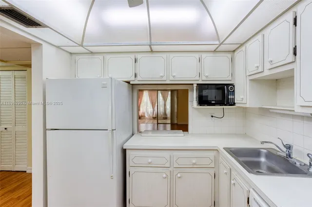 a kitchen with a sink a refrigerator and cabinets