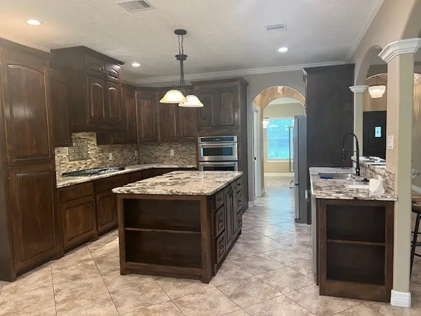 a kitchen with stainless steel appliances kitchen island granite countertop a refrigerator stove and sink