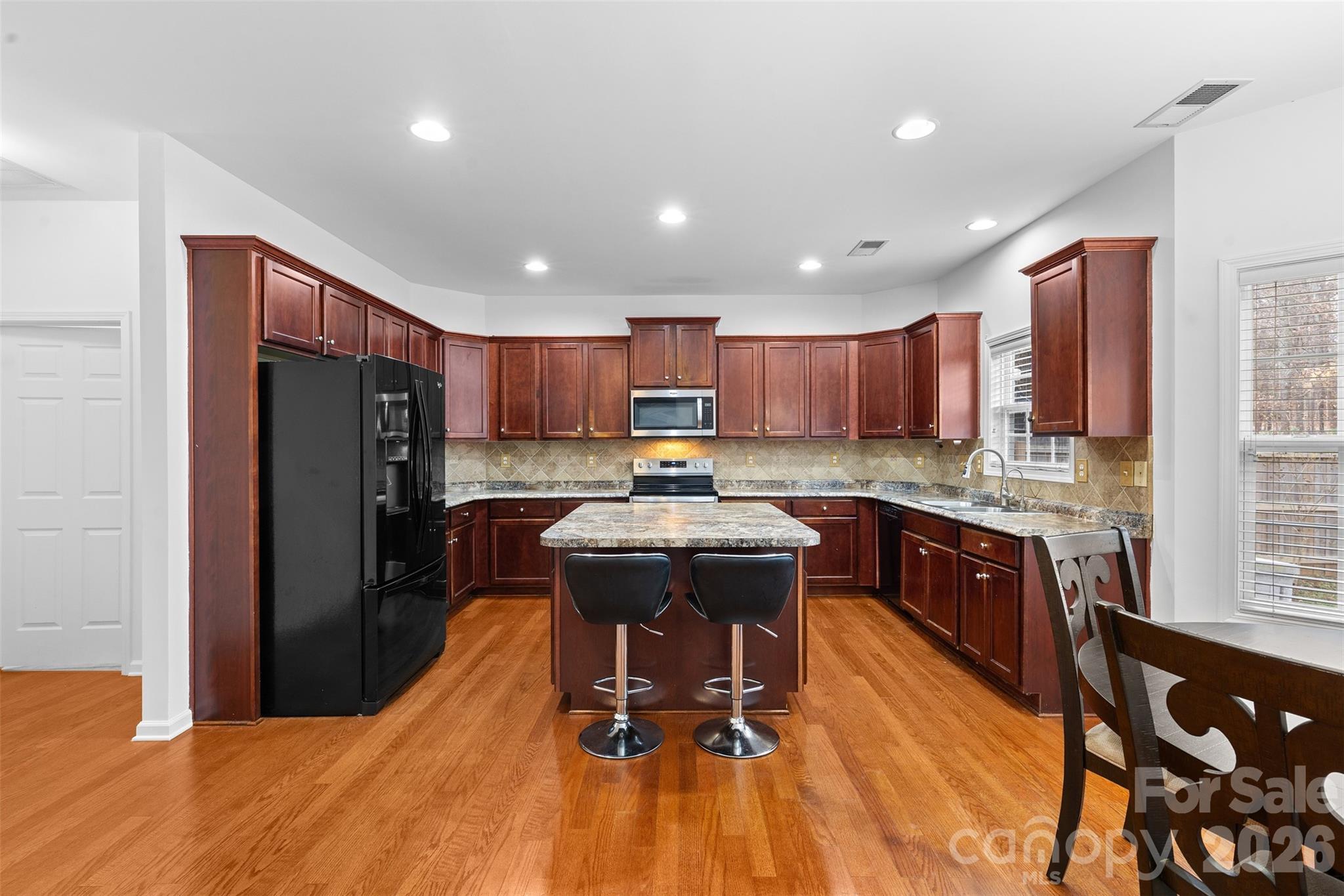 11919 Erwin Ridge Avenue Charlotte, NC 28213 - Photo 5 of 24 a kitchen with kitchen island granite countertop wooden floors stainless steel appliances a window