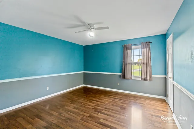 an empty room with wooden floor and fan