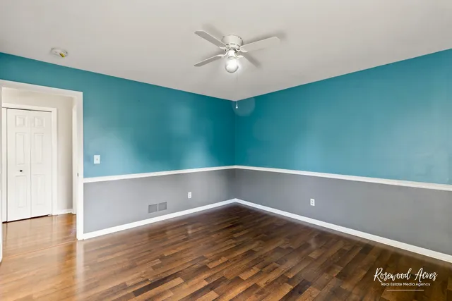 a view of a room with a ceiling fan and wooden floor