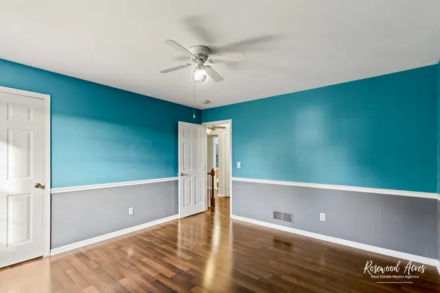 an empty room with wooden floor fan and windows